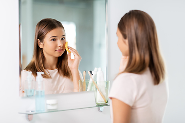 Image showing teenage girl cleaning face with sponge at bathroom