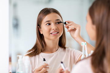 Image showing teenage girl applying mascara at bathroom