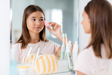 Image showing teenage girl applying foundation to face