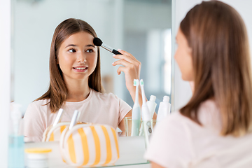 Image showing teenage girl applying powder to face at bathroom