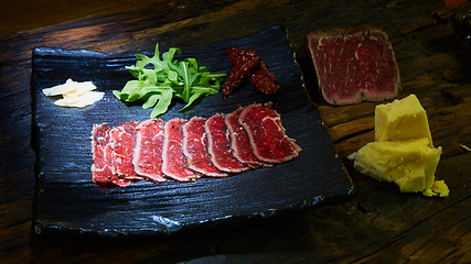 Image showing Barbecue wagyu roast beef sliced as top view on a metal tray with copy space right