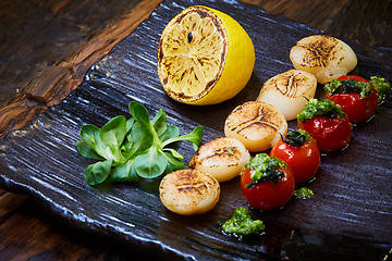 Image showing Fried scallops with tomatoes on a black plate. Shallow dof.