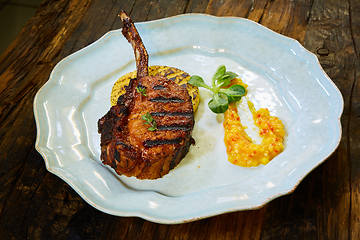 Image showing Roasted lamb ribs with spices and sauce on white plate. Shallow dof