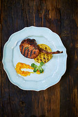 Image showing Roasted lamb ribs with spices and sauce on white plate. Shallow dof