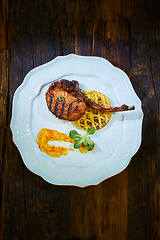 Image showing Roasted lamb ribs with spices and sauce on white plate. Shallow dof