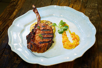 Image showing Roasted lamb ribs with spices and sauce on white plate. Shallow dof