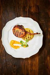 Image showing Roasted lamb ribs with spices and sauce on white plate. Shallow dof