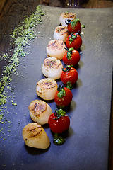 Image showing Fried scallops with tomatoes on a black plate. Shallow dof.