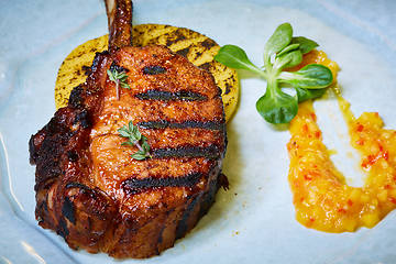 Image showing Roasted lamb ribs with spices and sauce on white plate. Shallow dof