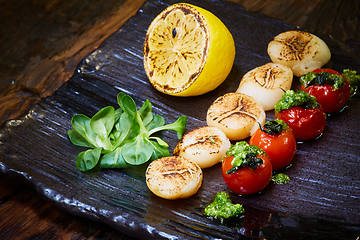 Image showing Fried scallops with tomatoes on a black plate. Shallow dof.