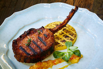 Image showing Roasted lamb ribs with spices and sauce on white plate. Shallow dof