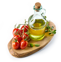 Image showing olive oil and tomatoes on wooden cutting board