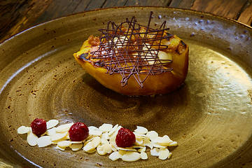 Image showing Grilled pear dessert decorated with chocolate and almonds