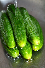 Image showing wash the cucumber in metal kitchen sink under water jet close-up