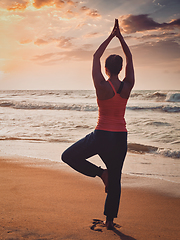 Image showing Young sporty fit woman doing yoga tree asana on beach