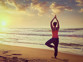 Image showing Young sporty fit woman doing yoga tree asana on beach