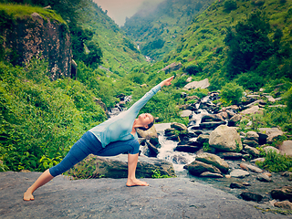 Image showing Woman practices yoga asana Utthita Parsvakonasana outdoors