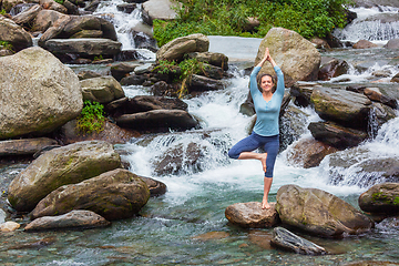 Image showing Woman in yoga asana Vrikshasana tree pose at waterfall outdoors