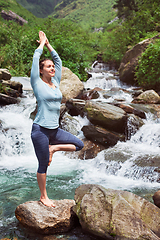 Image showing Woman in yoga asana Vrikshasana tree pose at waterfall outdoors