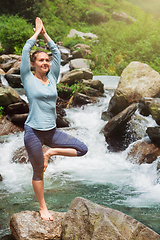 Image showing Woman in yoga asana Vrikshasana tree pose at waterfall outdoors