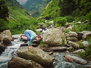 Image showing Woman doing Kakasana asana arm balance at waterfall