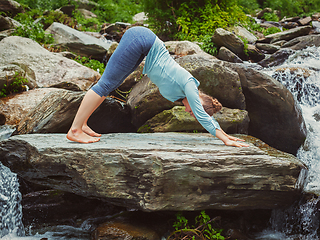 Image showing Young sporty fit woman doing yoga oudoors at tropical waterfall