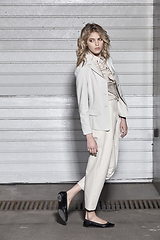 Image showing Full length fashion portrait of a woman standing against a wall on street. Street style