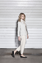 Image showing Full length fashion portrait of a woman standing against a wall on street. Street style