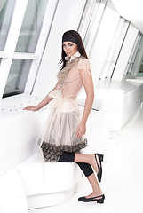 Image showing Full-length portrait young elegant woman in black leggings and beige dress. Fashion studio shoot