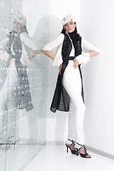 Image showing Beautiful young woman in white hat, high heels and white suit is standing, looking in camera. Full length studio shot on white background.