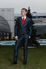 Image showing Portrait of an attractive young businessman in urban background wearing suit and necktie. Looking to the camera. Classic style.