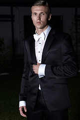 Image showing Portrait of an attractive young businessman in urban background wearing suit and necktie. Looking to the camera. Classic style. Studio shot