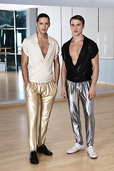 Image showing Two men in elegant sport suits posing in fitness gym. Young men in silver and gold sport leggings