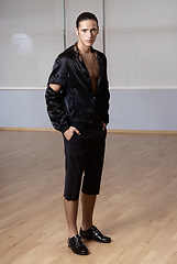 Image showing Man in elegant suite posing in fitness gym. High fashion young sexy man in black shorts and a black jacket.
