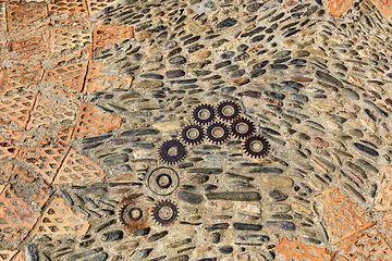 Image showing Unusual floor with pattern from pebbles, brick and rusty metal d