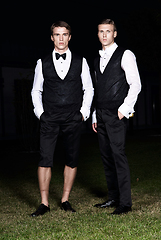 Image showing Fashion portrait of two young sexy handsome men models in casual cloth suit on green grass