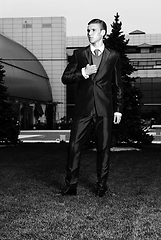 Image showing Portrait of an attractive young businessman in urban background wearing suit and necktie. Looking to the camera. Classic style. Studio shot