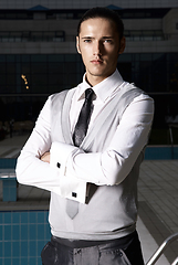 Image showing Portrait of an attractive young businessman in urban background wearing suit and necktie. Looking to the camera. Classic style.