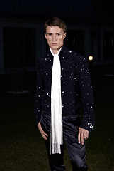 Image showing Male fashion, beauty concept. Portrait of young man with short wet hair wearing black suit, posing on street. Classic style.