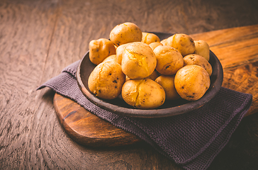 Image showing Boiled young potatoes in bowl on cutting board