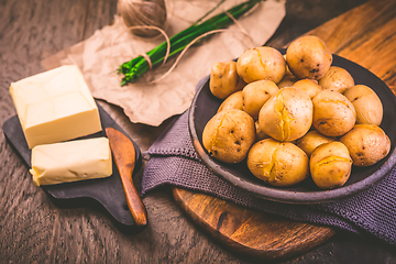 Image showing Boiled young potatoes with butter and chives on cutting board