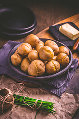 Image showing Boiled young potatoes with butter and chives on cutting board