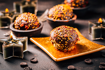 Image showing Small chocolate pastry cakes for Christmas with candles and ornaments