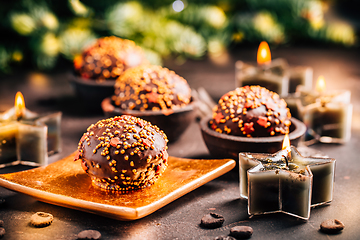 Image showing Small chocolate pastry cakes for Christmas with candles and ornaments