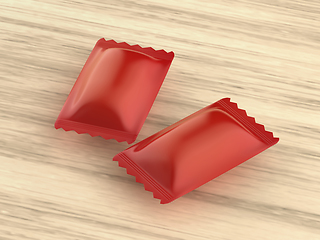 Image showing Two red packagings for hard candies on wooden table