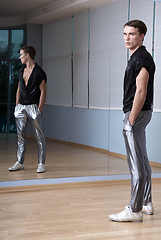 Image showing Man in elegant sport suit posing in fitness gym. Young man in silver sport leggings