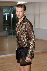 Image showing Man in elegant suite posing in fitness gym. High fashion young sexy man in shorts and a shirt decorated with gold.