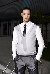 Image showing Portrait of an attractive young businessman in urban background wearing suit and necktie. Looking to the camera. Classic style.