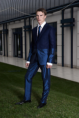 Image showing Portrait of an attractive young businessman in urban background wearing blue suit and necktie. Looking to the camera. Classic style.