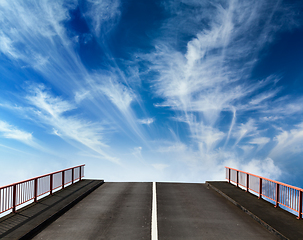 Image showing Asphalt road going into sky with clouds